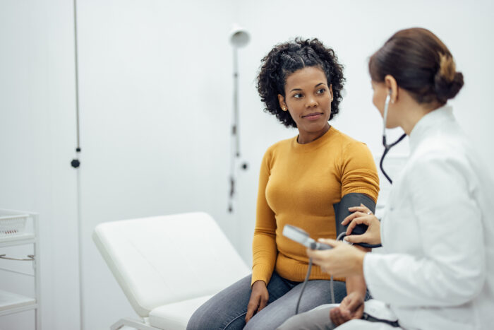 woman and nurse taking blood pressure