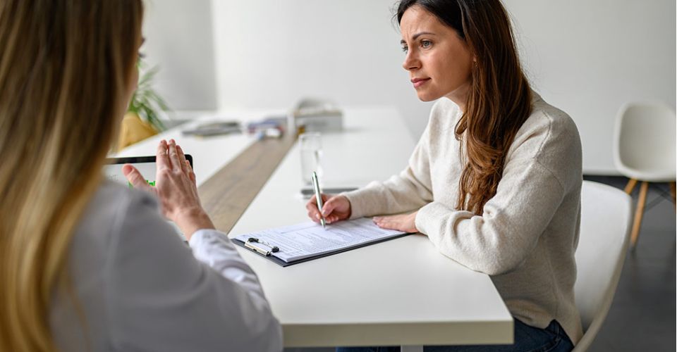Woman interviews other woman and takes notes
