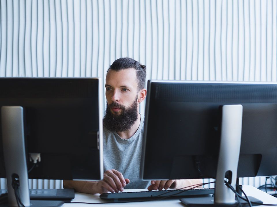 man works on 2 monitors