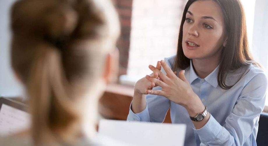 A woman converses with another woman in a professional office setting. 