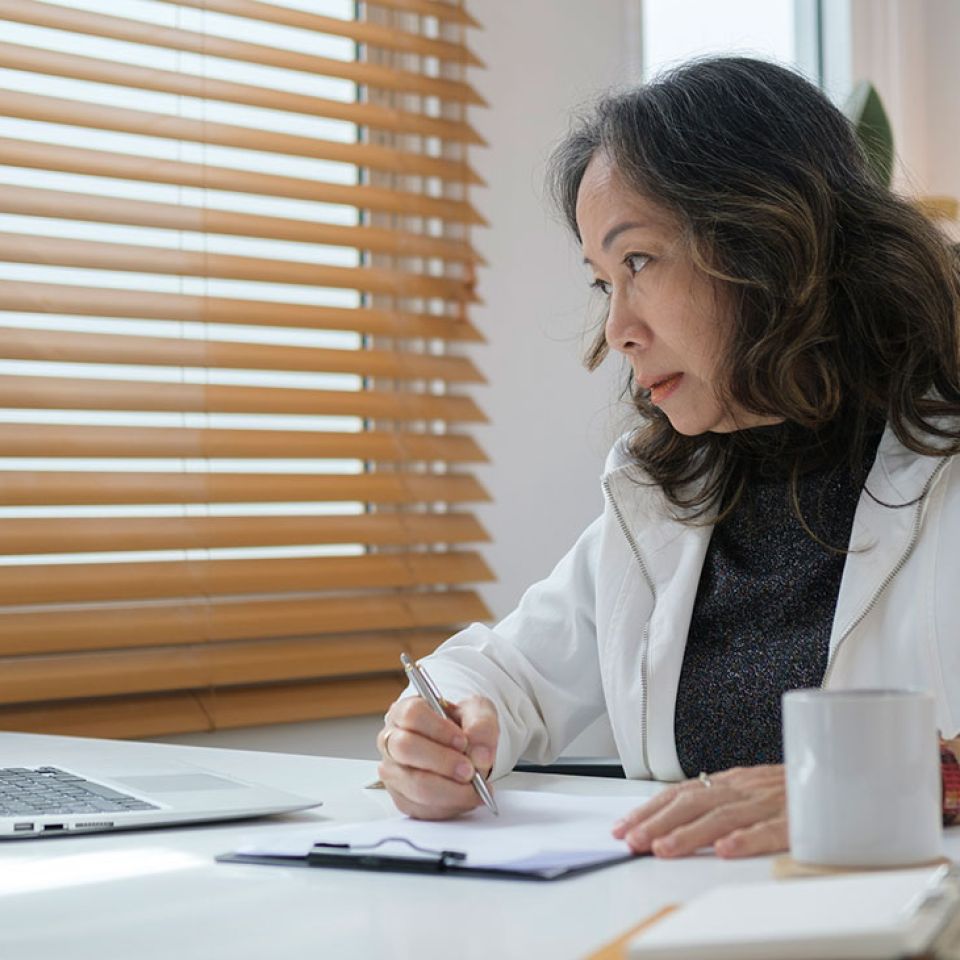 female doctor looks over computer and fills in report