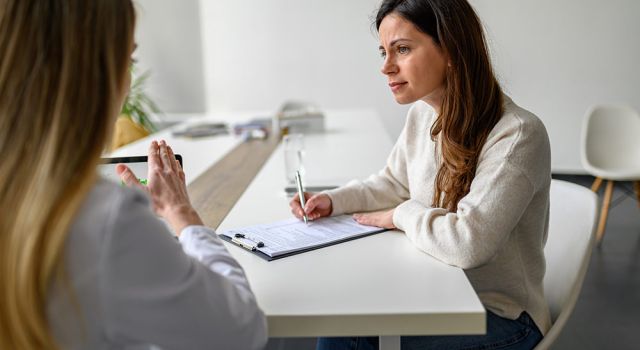 Woman interviews other woman and takes notes