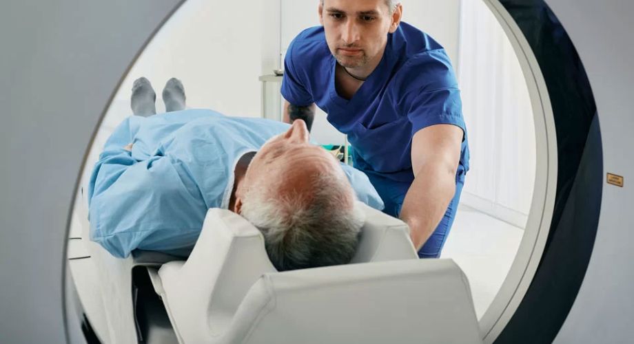 A man lies inside an MRI machine while a doctor conducts an examination. 