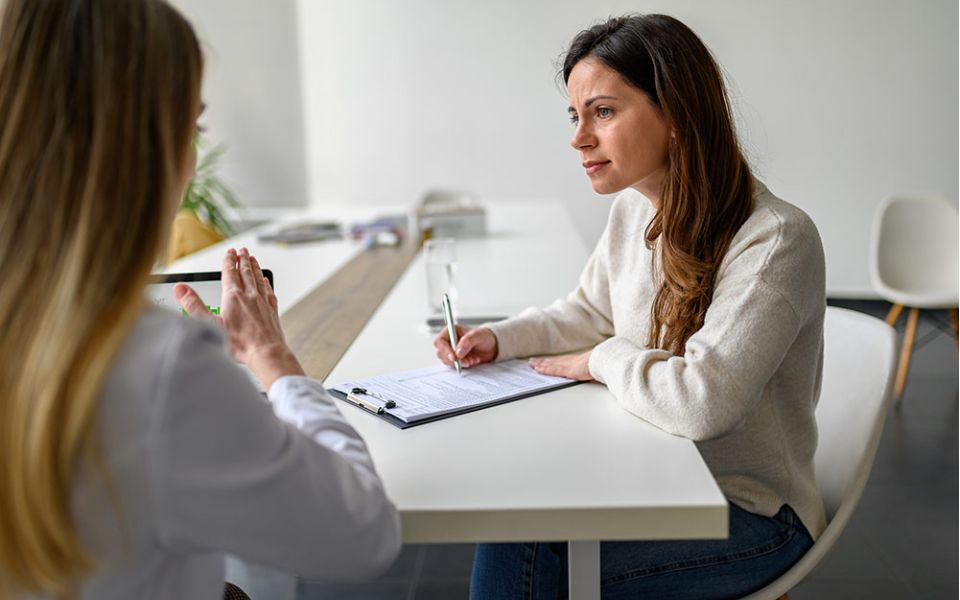 Woman interviews other woman and takes notes