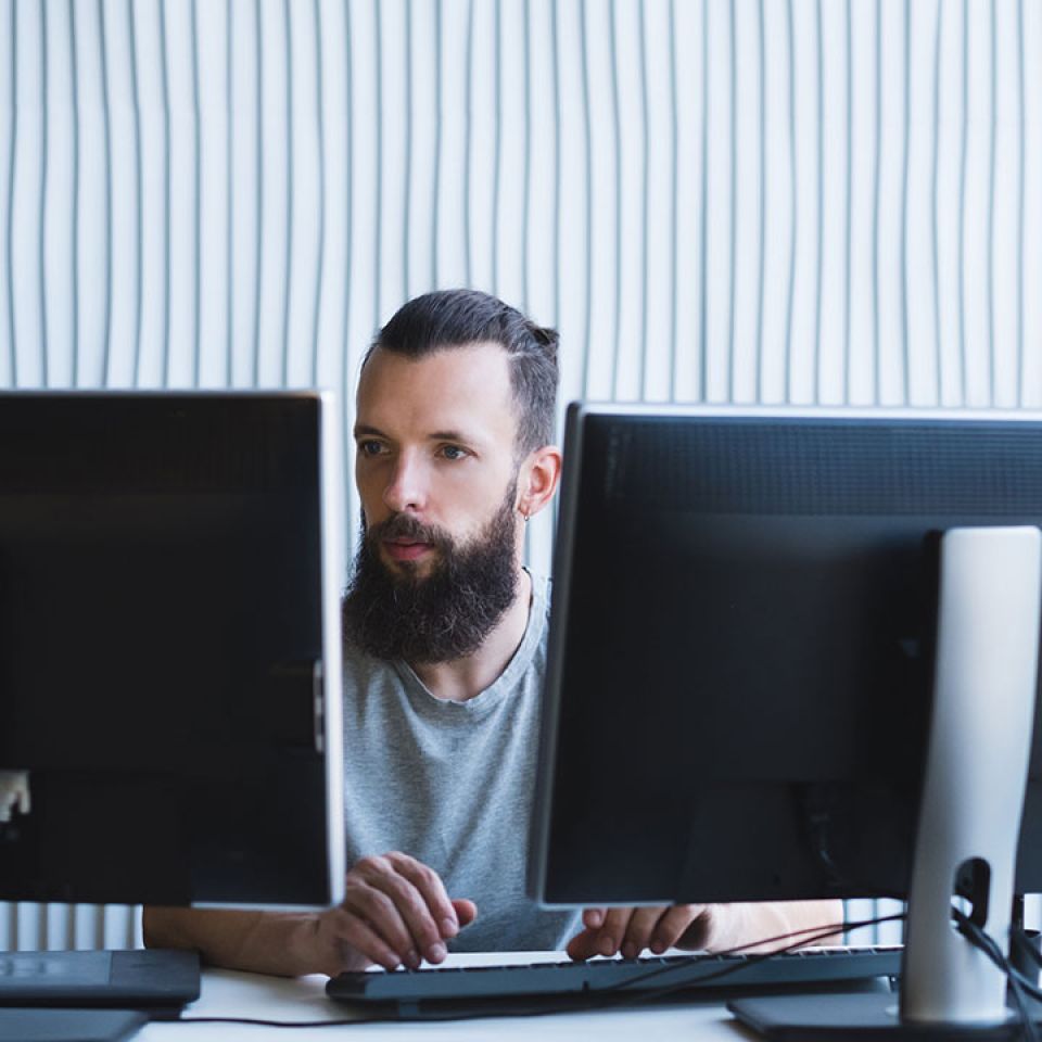 man works on 2 monitors