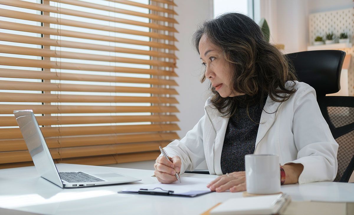 female doctor looks over computer and fills in report